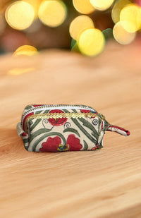 Decorative pouch with floral pattern on a wooden surface with blurred lights in the background